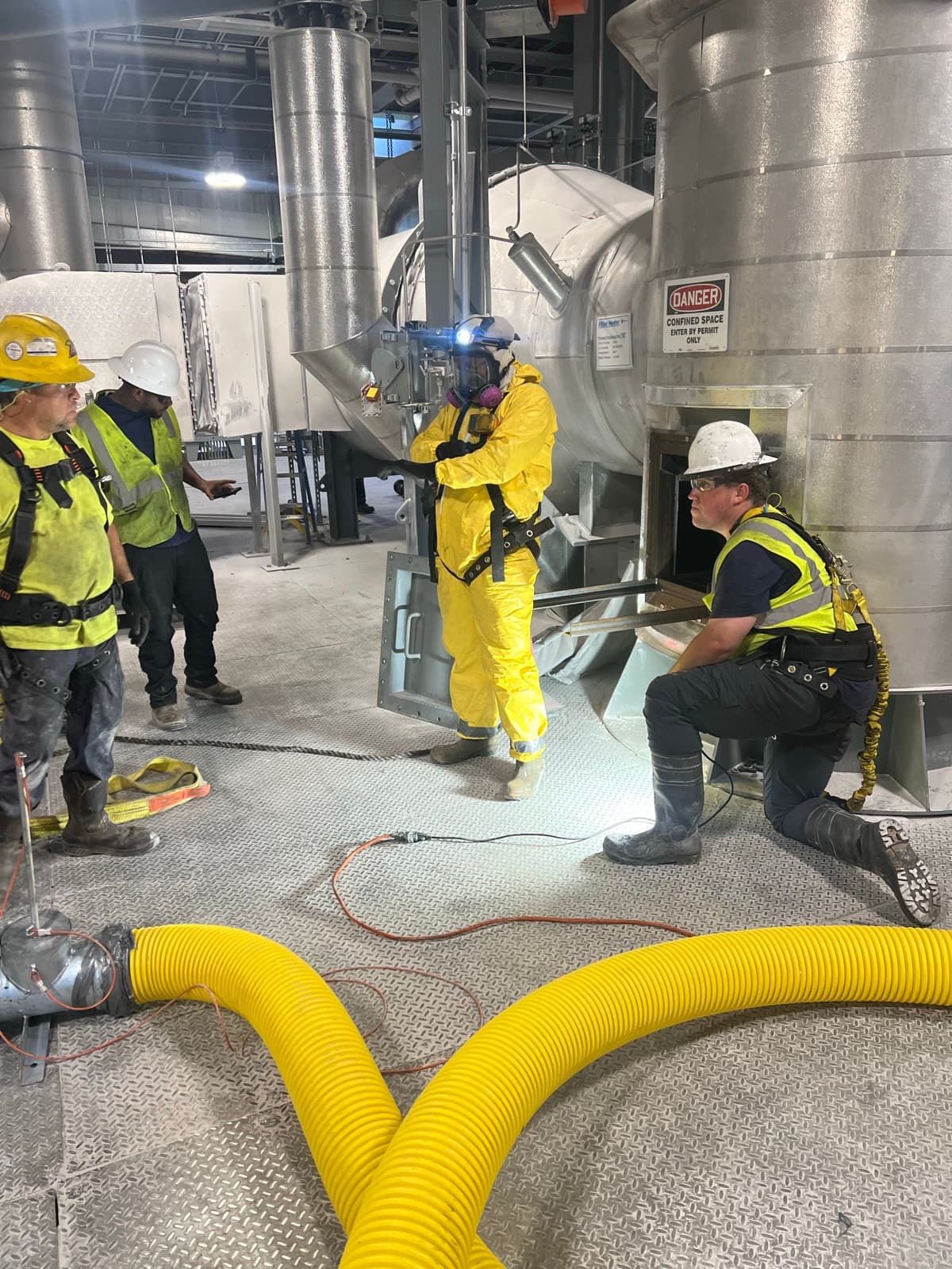 Cowart crew performing a confined-space entry with proper PPE and an outside attendant