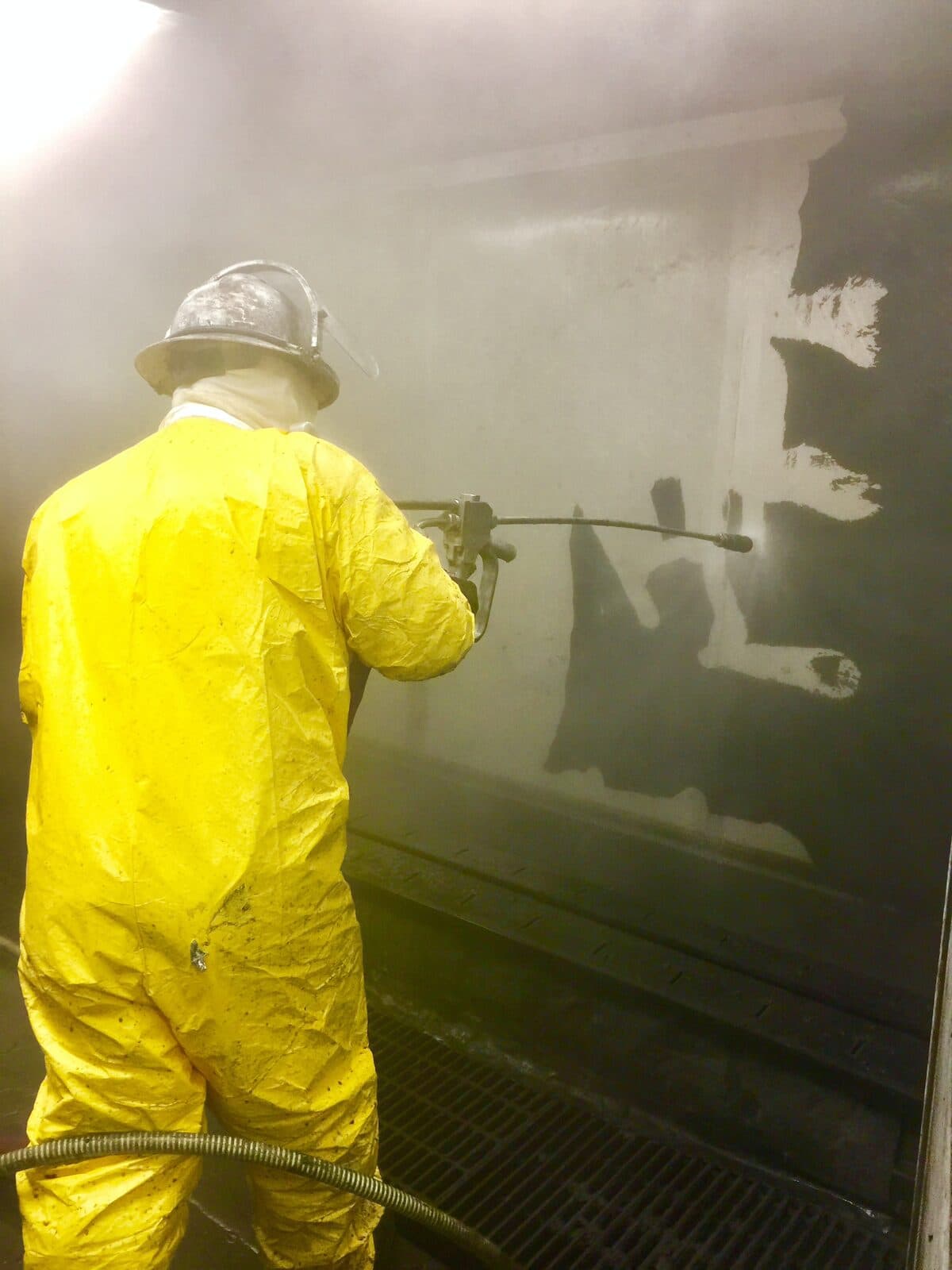 Cowart operator in PPE hydro-blasting an interior tank wall