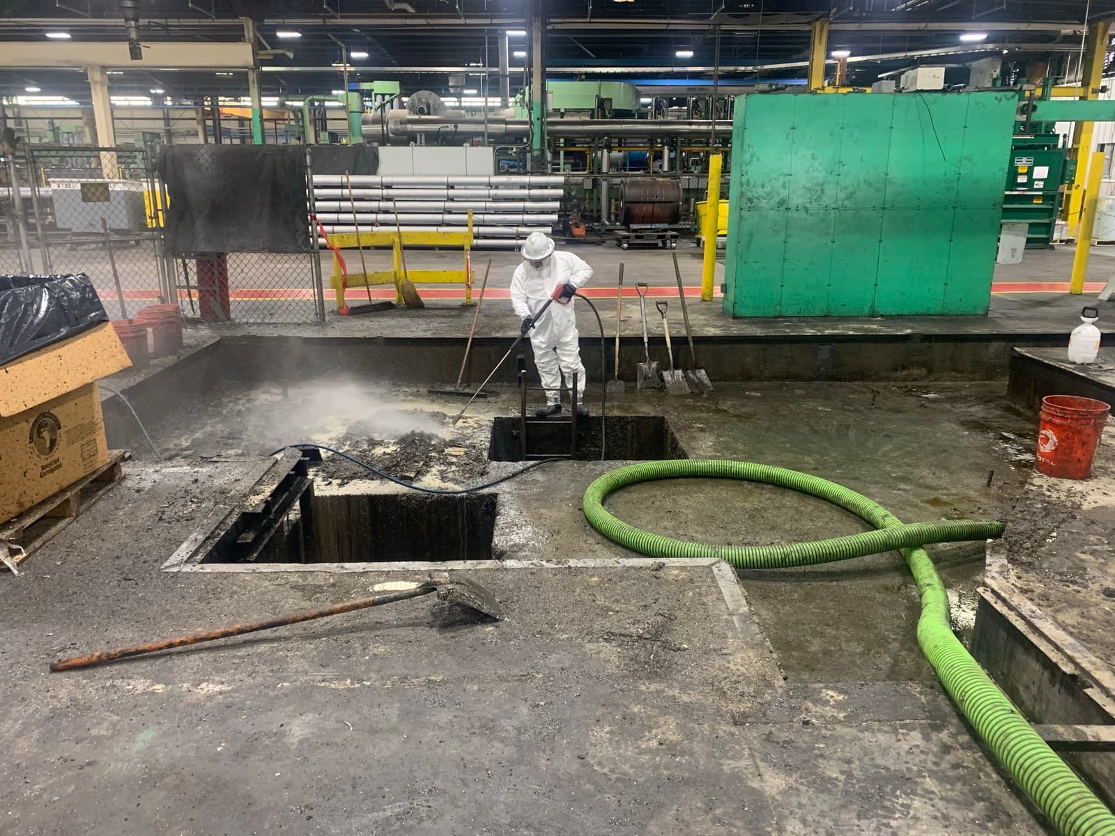 Cowart crew pressure-washing a sludge pit inside an industrial facility